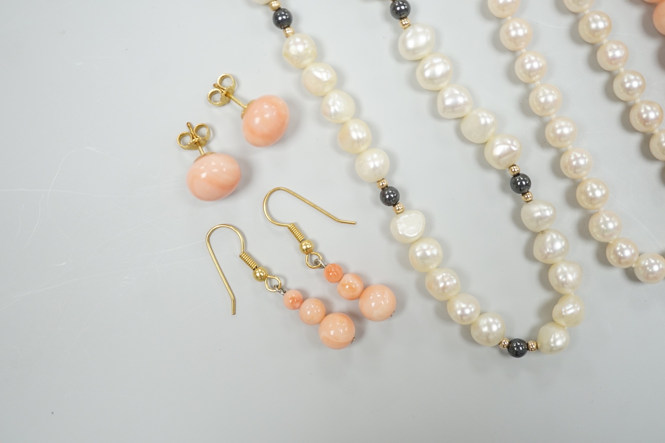 Two modern single strand cultured pearl necklaces, both with 375 clasp, one with hematite beads, longest 42cm, together with two modern coral bead necklaces, one with pair of matching drop earrings.